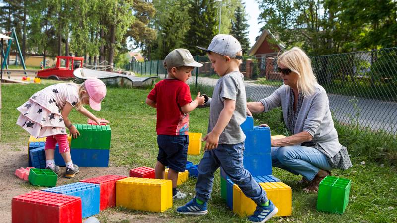 Barn leker med legobitar på gården.